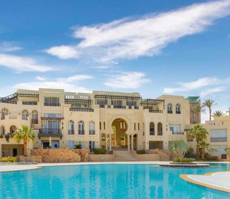 赫尔格达Azzurra two-bedrooms apartment at Sahl Hasheesh的一座大型建筑,前面设有一个游泳池
