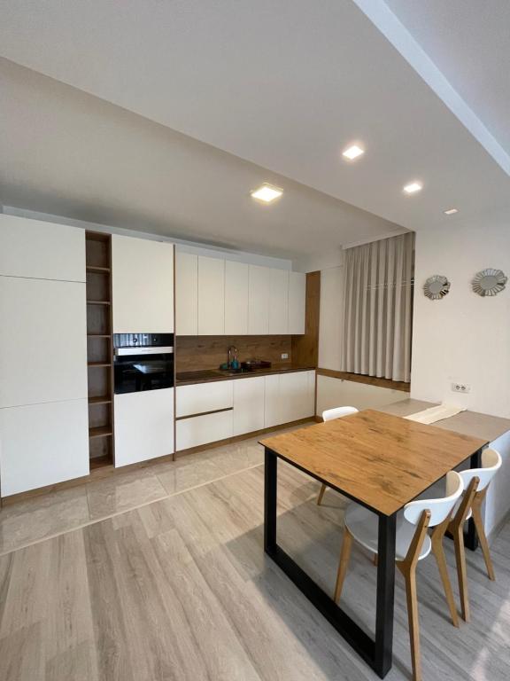 普里什蒂纳Plis Apartment II的厨房配有木桌和白色橱柜。