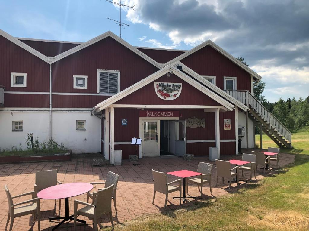 BjästaSkulesjön Hotell的前面的红色谷仓,配有桌椅