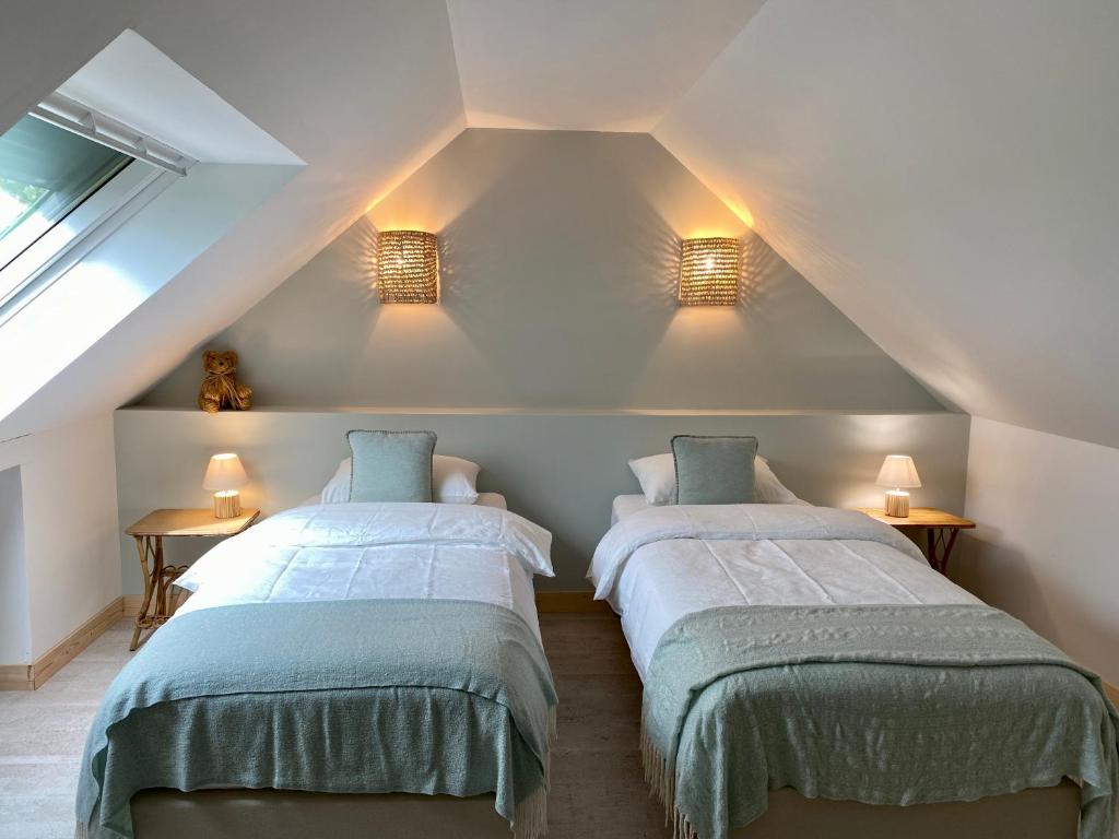普卢贡韦兰La Grange Neuve的阁楼卧室配有两张床和两盏灯。