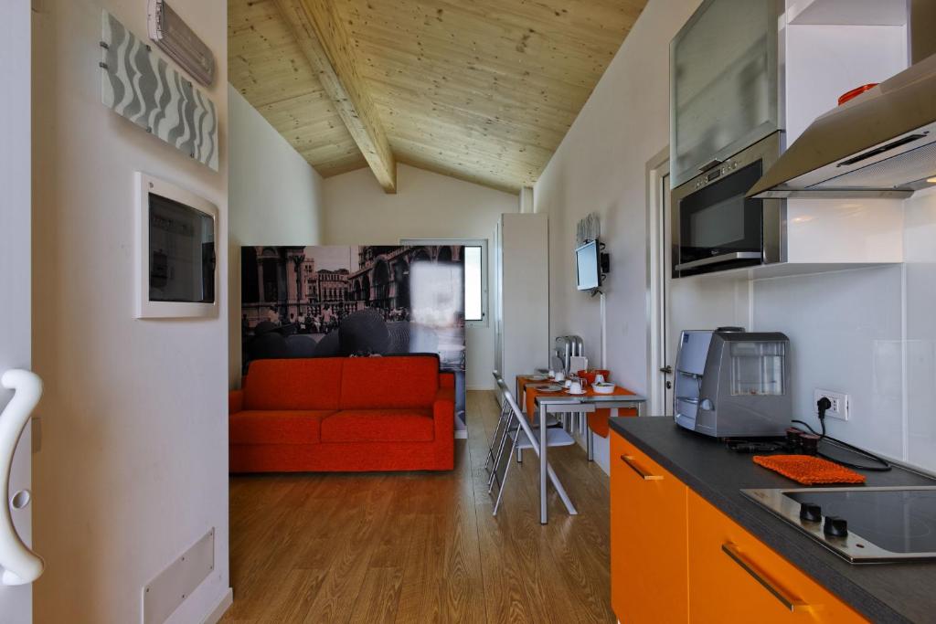 法瓦罗威尼托生态威尼斯公寓的厨房以及带红色沙发的起居室。