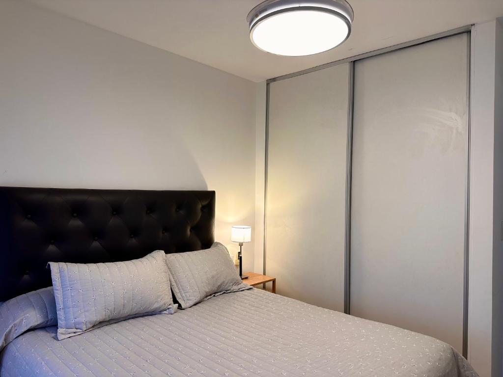 洛马斯-德萨莫拉Modern&Nordic Apartament Lomitas (2 ambientes)的一间卧室配有一张带黑色床头板的床