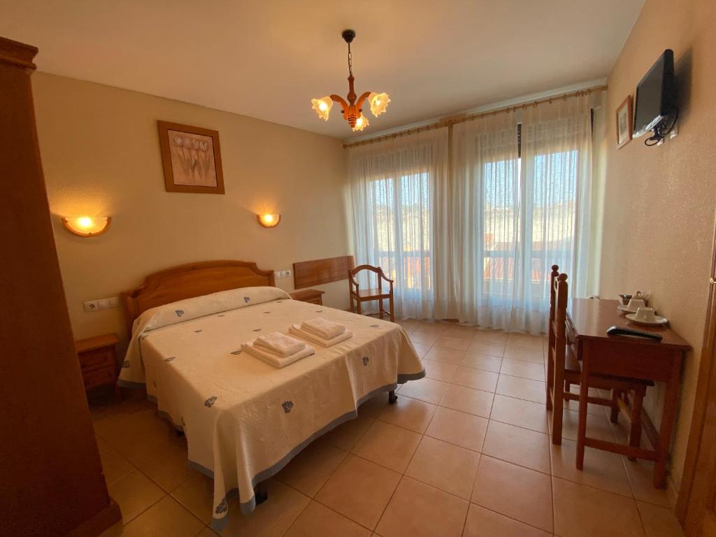 罗德里戈城Hostal Jose Mari的一间卧室配有一张床、一张桌子和一个窗户。