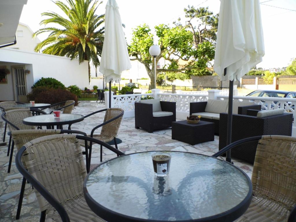 阿兰扎达小树林酒店的一个带桌椅和白色遮阳伞的庭院。