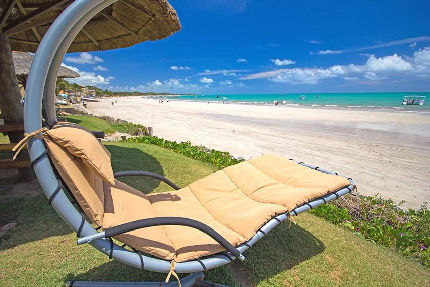 马拉戈日Pousada Portal do Maragogi的海滩边的遮阳伞下的沙滩椅