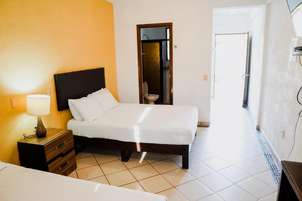 锡瓦塔塔内霍HOTEL ROBLE ZIHUATANEJO的一间卧室配有一张床、一张桌子和一盏灯