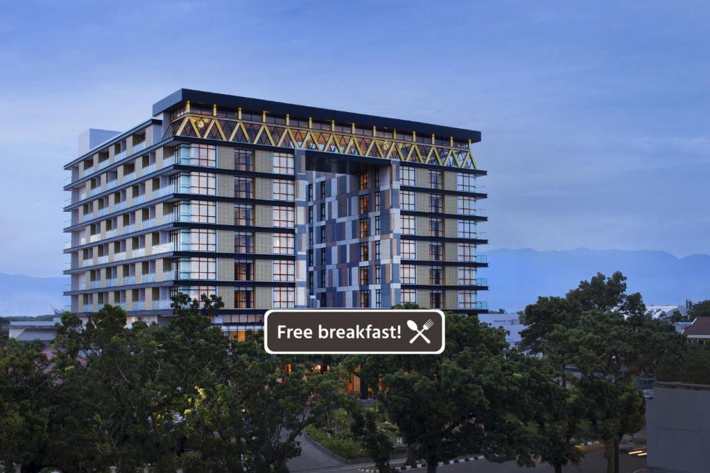 巴东Hotel Santika Premiere Padang的高层建筑前的免费早餐标志