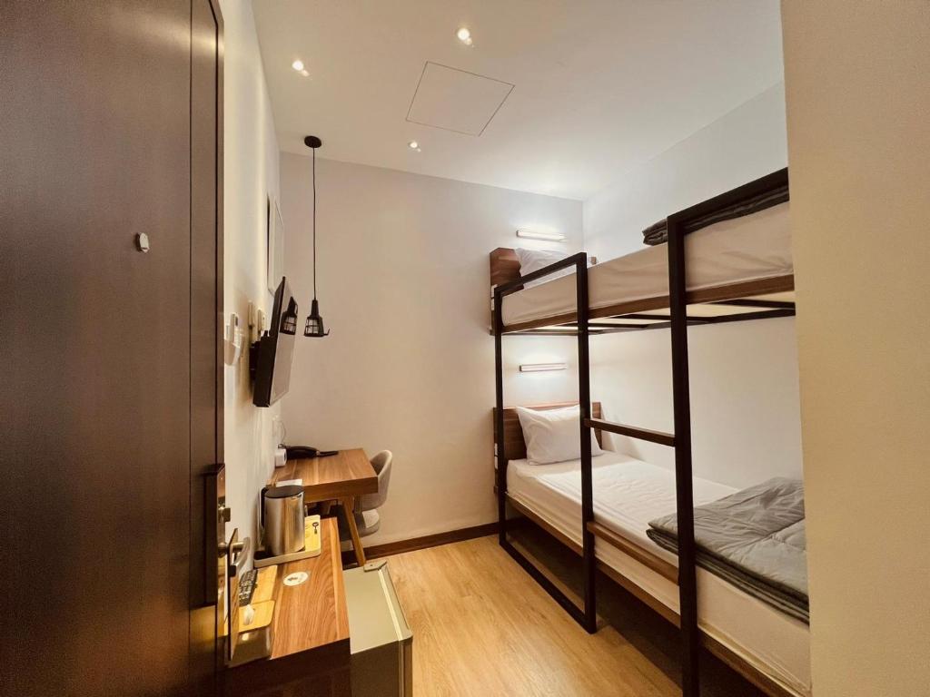 巴淡岛中心oxy suites G-03 at Shop House Meisterstadt Pollux Habibie的小房间设有两张双层床和一张书桌