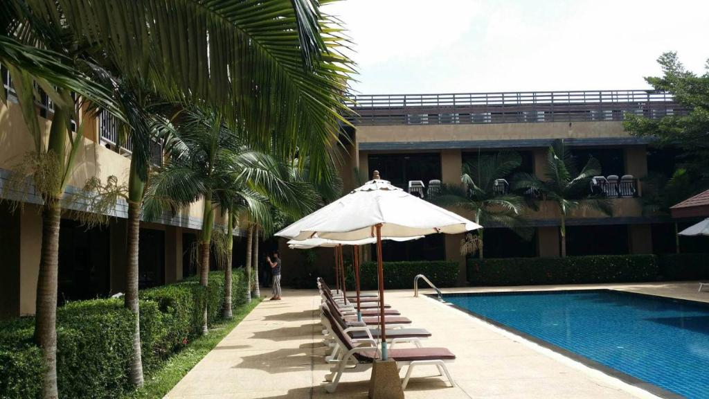 奈扬海滩Naiyang Beach Hotel SHA Plus的一座带椅子和遮阳伞的游泳池位于大楼旁