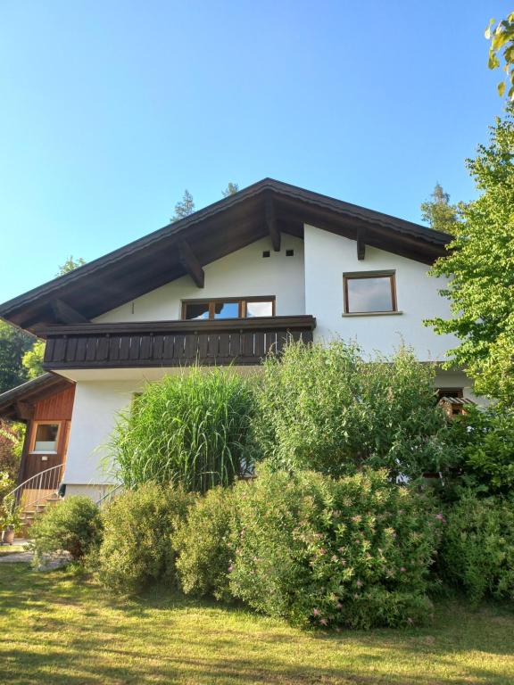 SchwarzachFerienwohnung in Schwarzach Vorarlberg的白色的房子,有黑色的屋顶和灌木丛
