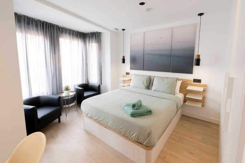 卡斯特利翁-德拉普拉纳Apartamento Capri Living Suites en Castellon的一间卧室配有一张床、一张桌子和一把椅子
