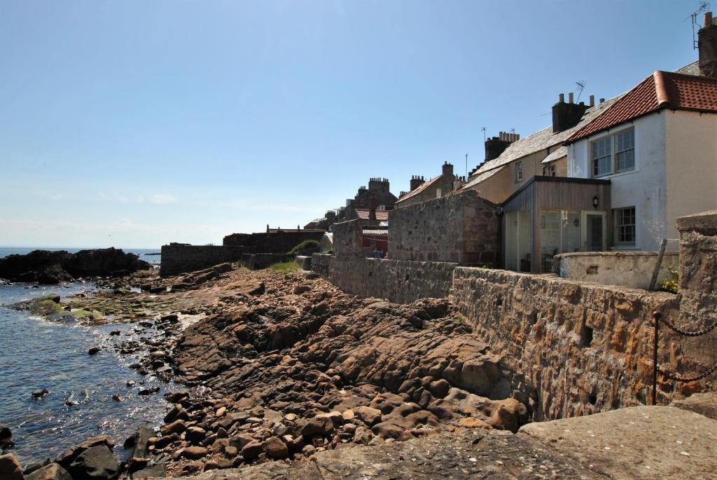 安斯特拉瑟Aqua Vista- seafront cottage Cellardyke的水边岩石上的一群房子