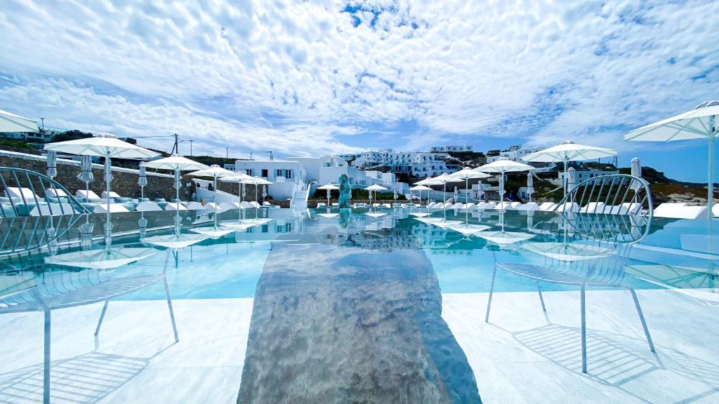 米克诺斯城米科诺斯湾度假酒店&别墅 的一个带椅子和遮阳伞的游泳池