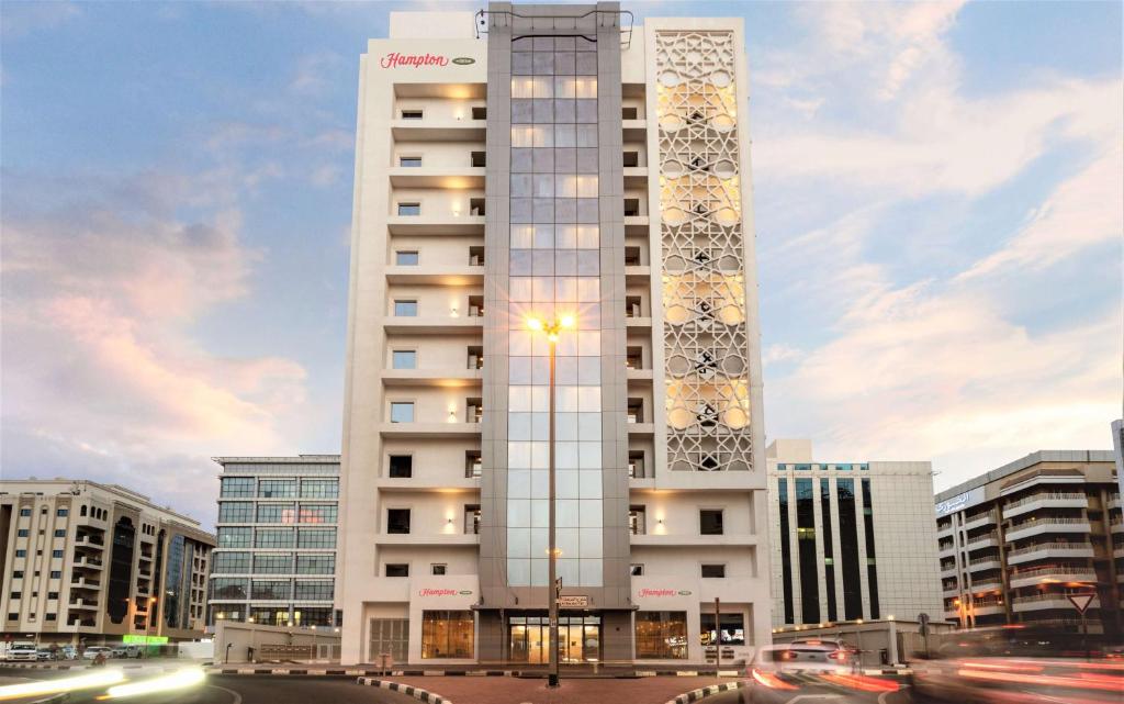 迪拜Hampton By Hilton Dubai Al Barsha的一座高大的白色建筑,上面有时钟