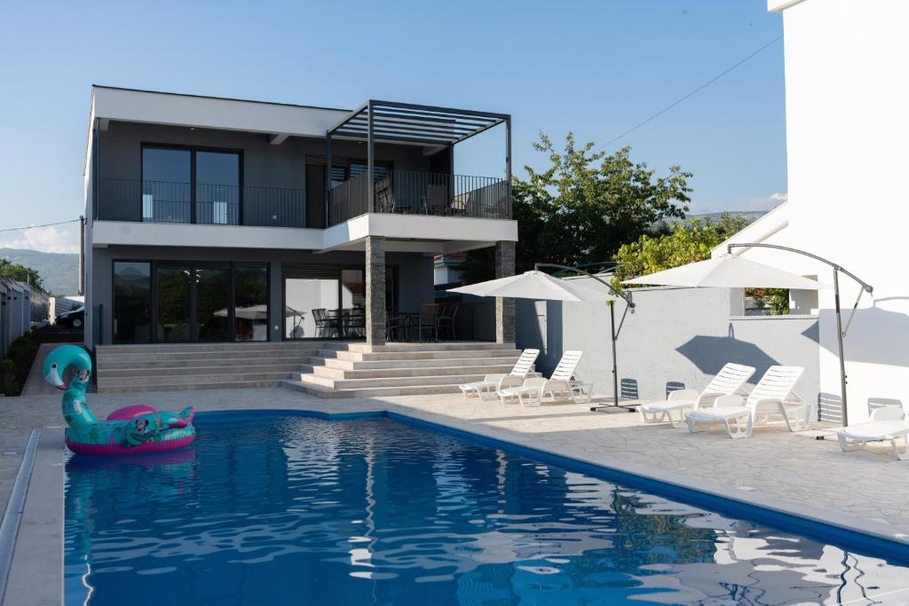 莫斯塔尔Villa Zulfikar的一座房子,前方设有游泳池,面朝泳池面