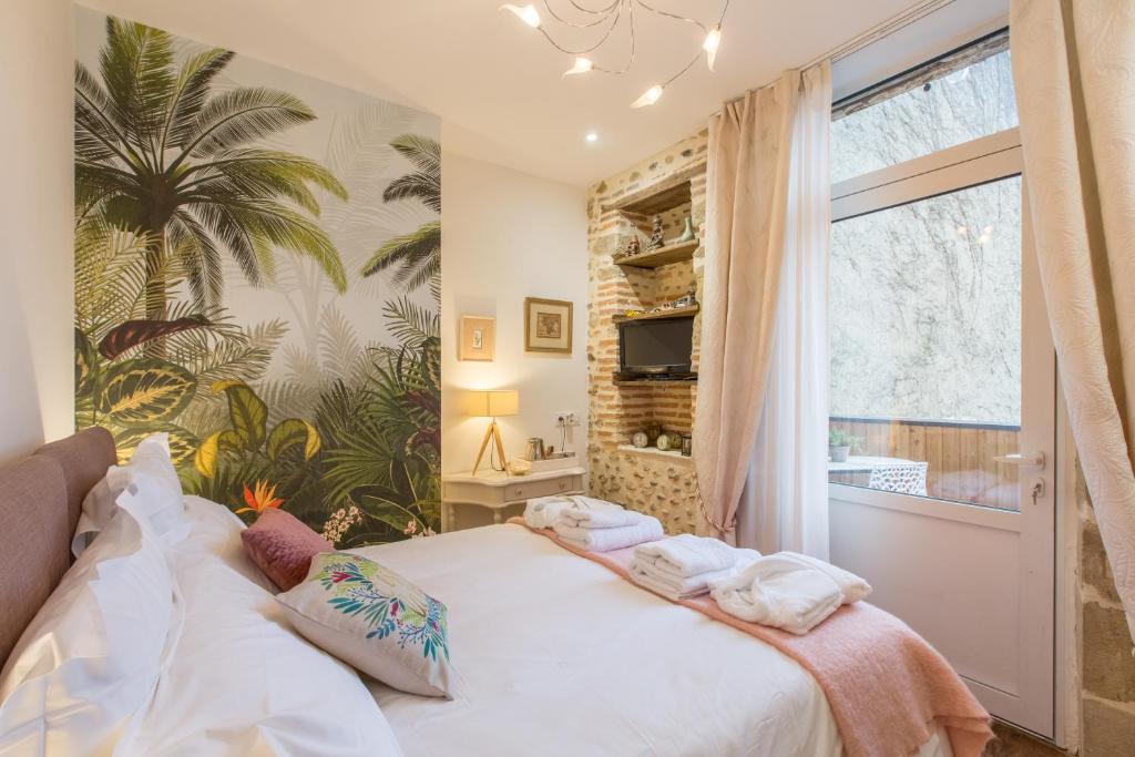 阿杜尔河畔艾尔"Le Jardin sur l'Eau "chambres d'hôtes et appartement tout confort的一间卧室配有一张大床和毛巾