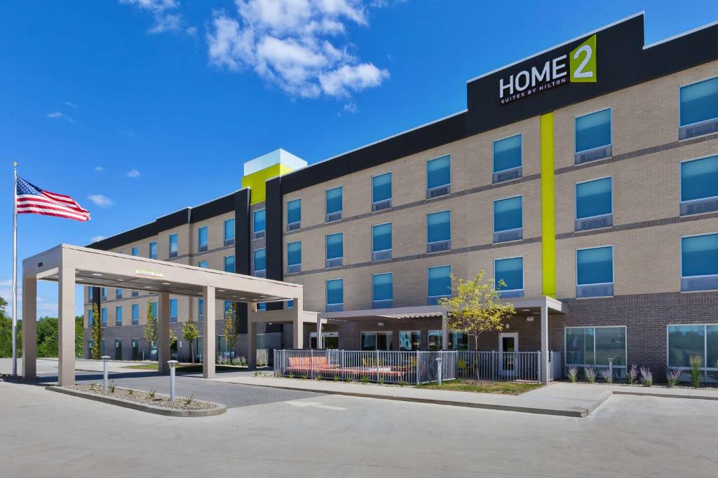 巴特尔克里克Home2 Suites By Hilton Battle Creek, Mi的前面有美国国旗的酒店大楼