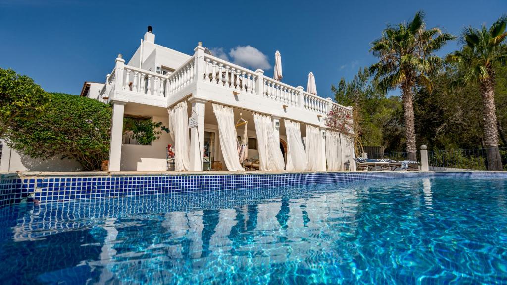 圣安东尼奥Can Paradís的白色的房子,设有游泳池和棕榈树
