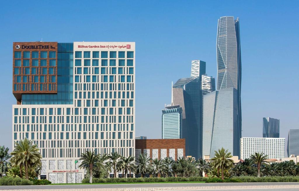 利雅德Hilton Garden Inn Riyadh Financial District的拥有高楼和棕榈树的城市天际线