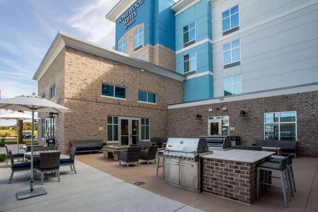 默特尔比奇Homewood Suites By Hilton Myrtle Beach Coastal Grand Mall的一个有桌椅的露台和一栋建筑