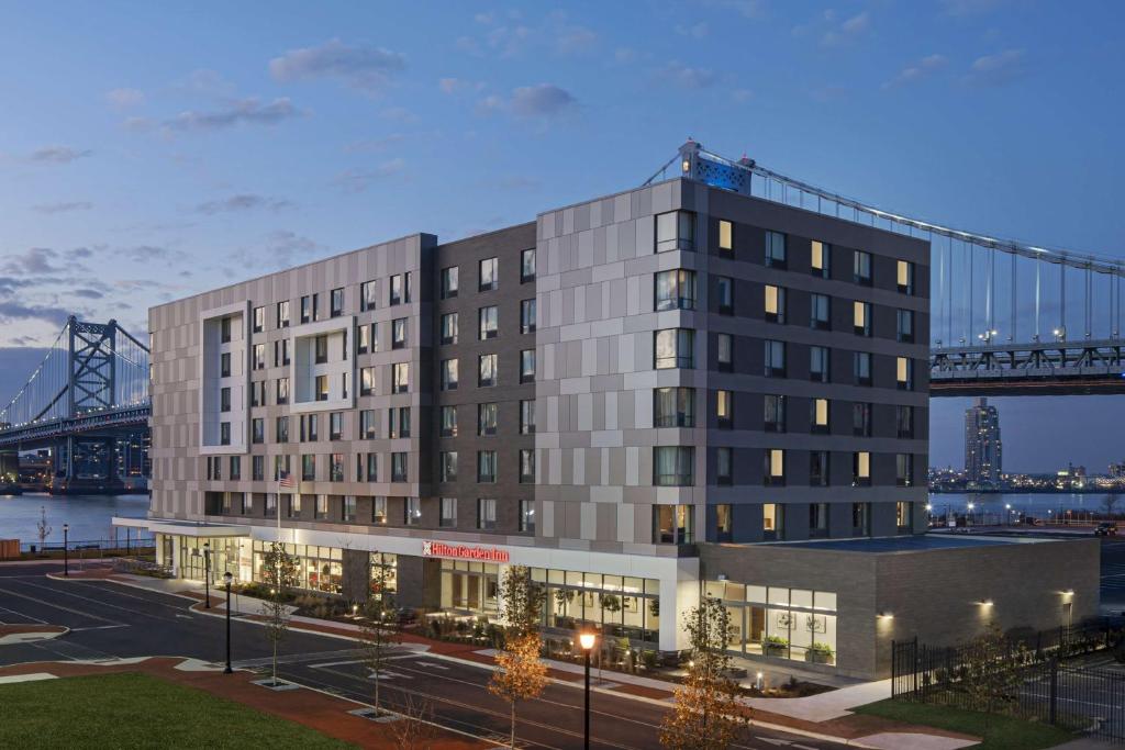 CamdenHilton Garden Inn Camden Waterfront Philadelphia的背景中带有桥梁的建筑物的 ⁇ 染