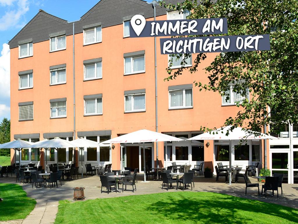 霍登哈根ACHAT Hotel Lüneburger Heide的大楼前设有桌椅的酒店