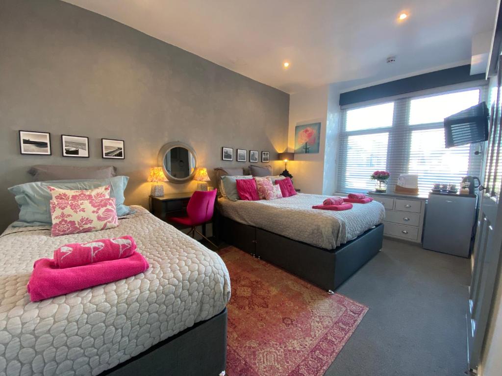 布莱克浦The Mayfield Boutique Guest House的一间卧室配有两张带粉红色枕头的床