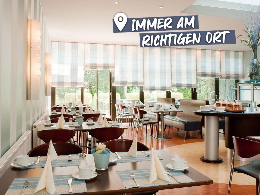 雷根斯堡ACHAT Hotel Regensburg im Park的一间带桌椅和标志的餐厅