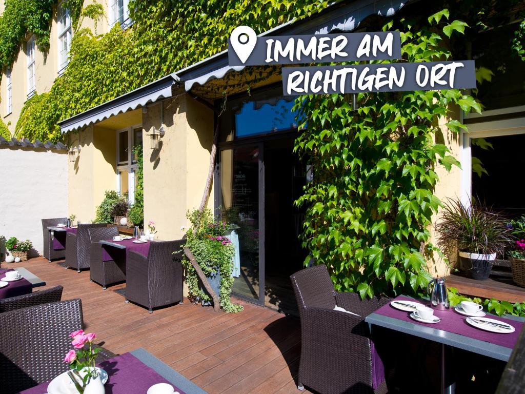 雷根斯堡ACHAT Hotel Regensburg Herzog am Dom的庭院内的餐厅,配有桌椅