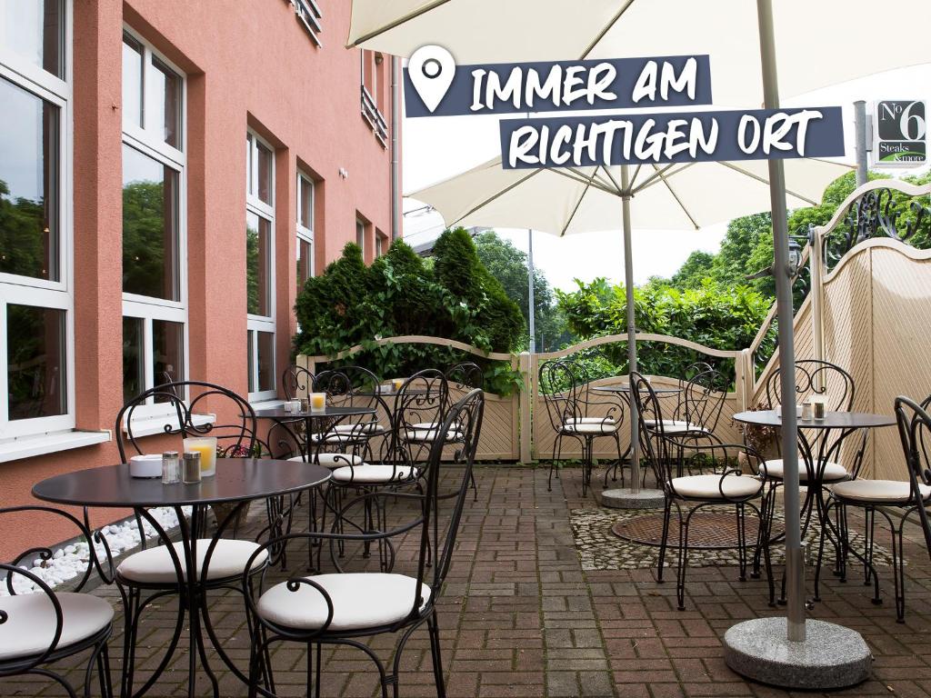 施韦青根ACHAT Hotel Schwetzingen Heidelberg的一个带桌椅和遮阳伞的户外庭院