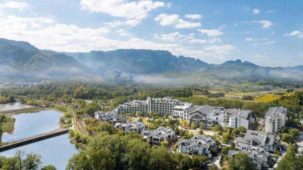 台州台州神仙居希尔顿逸林酒店的享有河流和山脉的度假村的空中景致