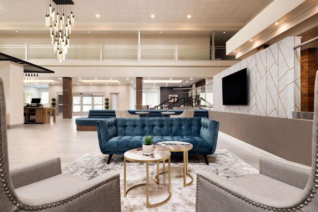 沃思堡Doubletree By Hilton Fort Worth South的大堂设有蓝色的沙发、电视和桌子。