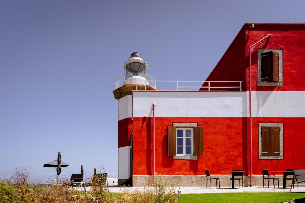 康培斯Resort Faro di Punta Fenaio的一座红色和白色的建筑,设有灯塔