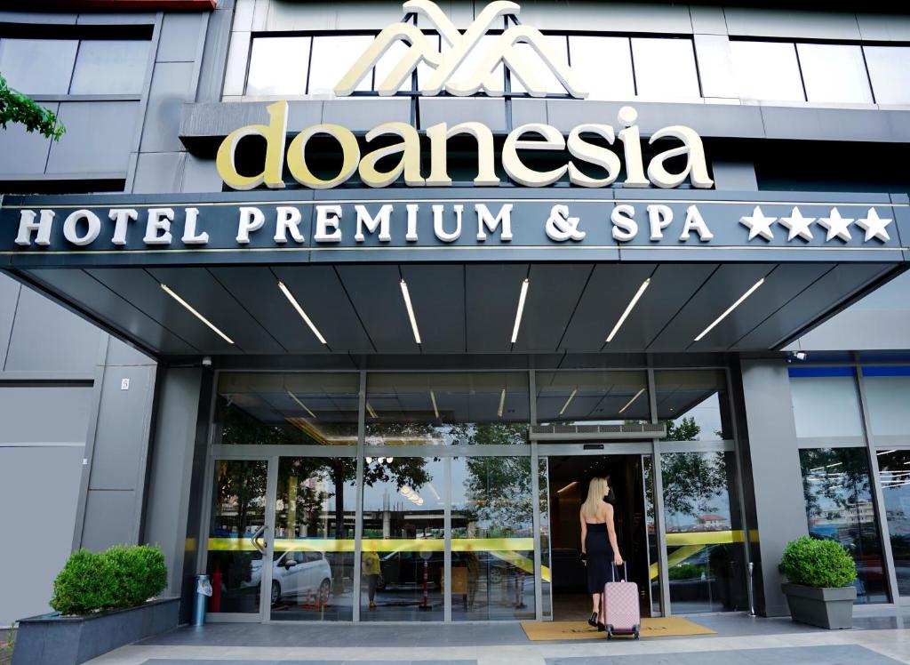 地拉那Doanesia Premium Hotel & Spa的一名妇女走出酒店和水疗中心