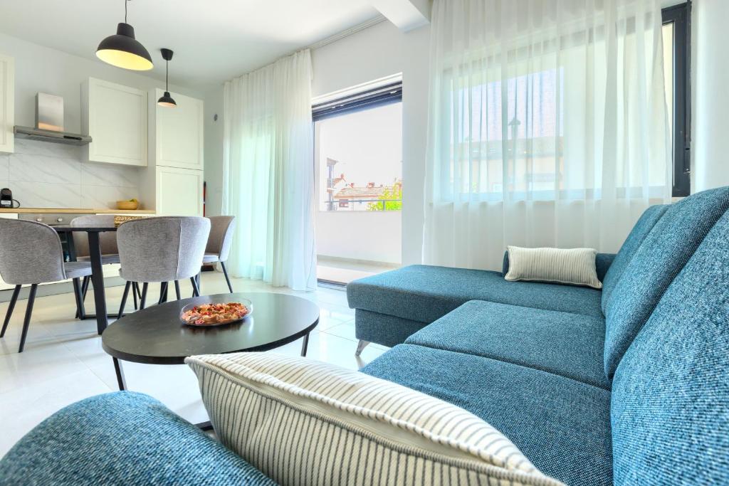 罗维尼Apartments La Scogliera Rovinj的客厅配有蓝色的沙发和桌子