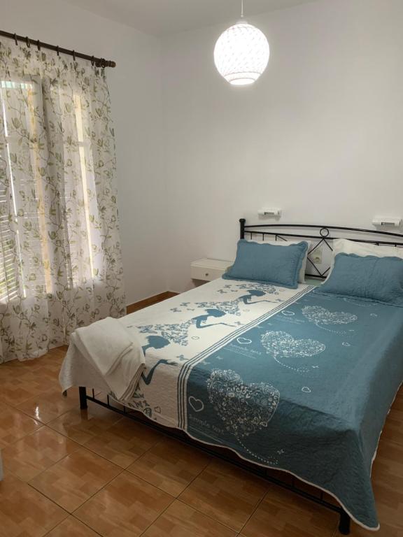 米克罗斯雅洛斯ΜΕΤΑΧΑ的一间卧室配有一张带蓝色棉被的床