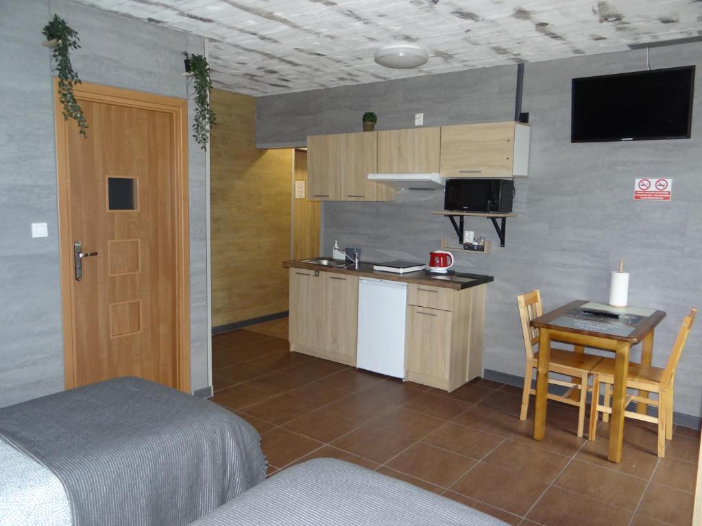 普沃茨克Hotel Apartamenty 72的一间卧室配有一张床铺和一张桌子,还设有一间厨房