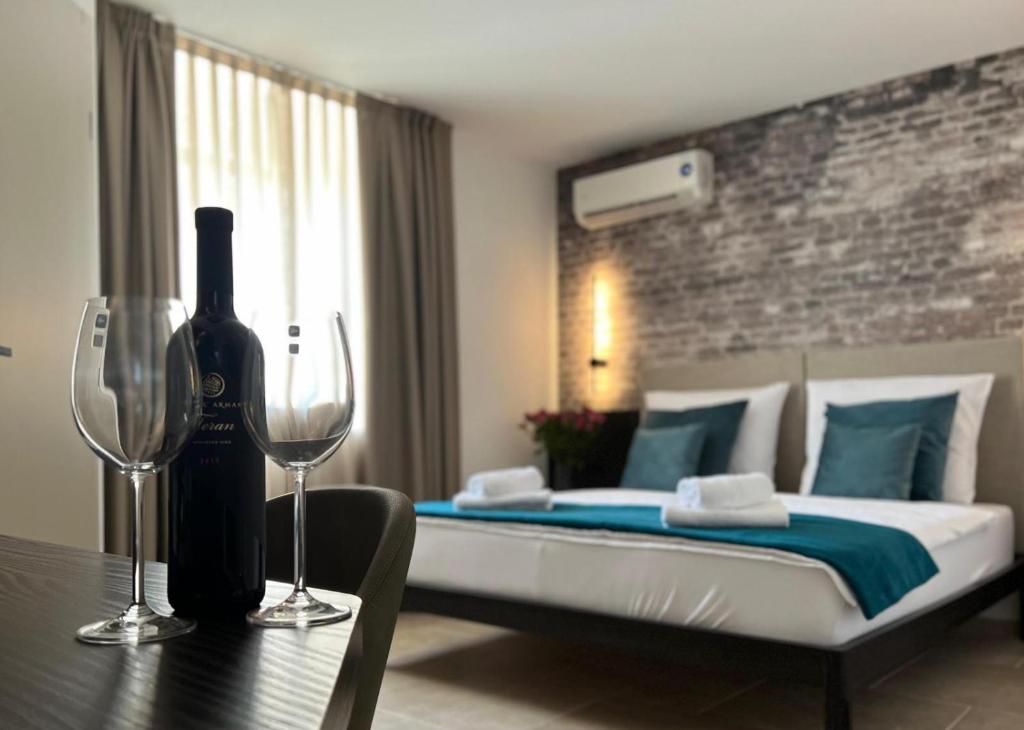 普拉Arena Prestige Rooms的一间卧室配有一张床,桌子上备有一瓶葡萄酒