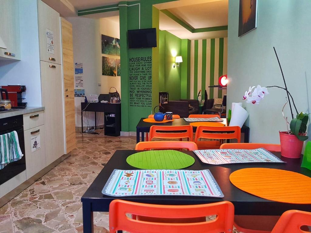 米拉佐Driade H的一间餐厅设有桌子和橙色椅子,拥有绿色的墙壁