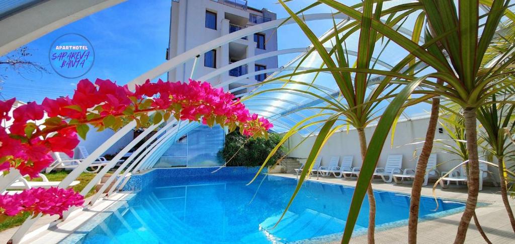 萨帕雷瓦巴尼亚ENIS Hotel с минерален басейн的一座拥有粉红色花卉和棕榈树的度假游泳池