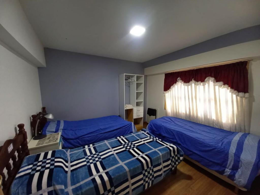乌斯怀亚hostel comunidad Ushuaia的一间卧室设有两张带蓝色床单的床和窗户。