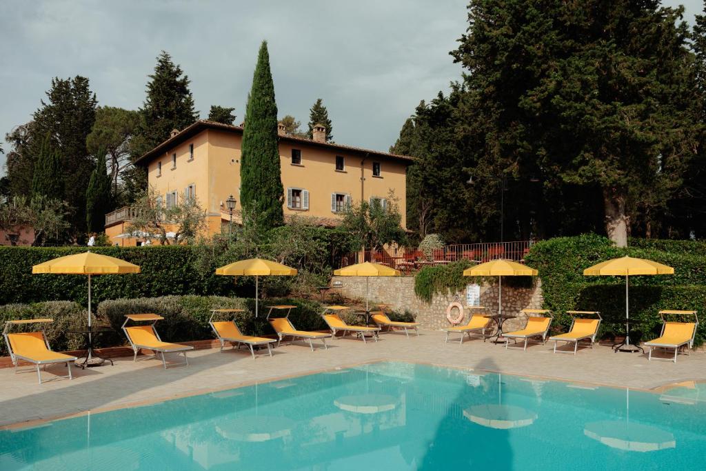 蒙泰斯佩尔托利Villa La Cappella的大楼前的带椅子和遮阳伞的游泳池