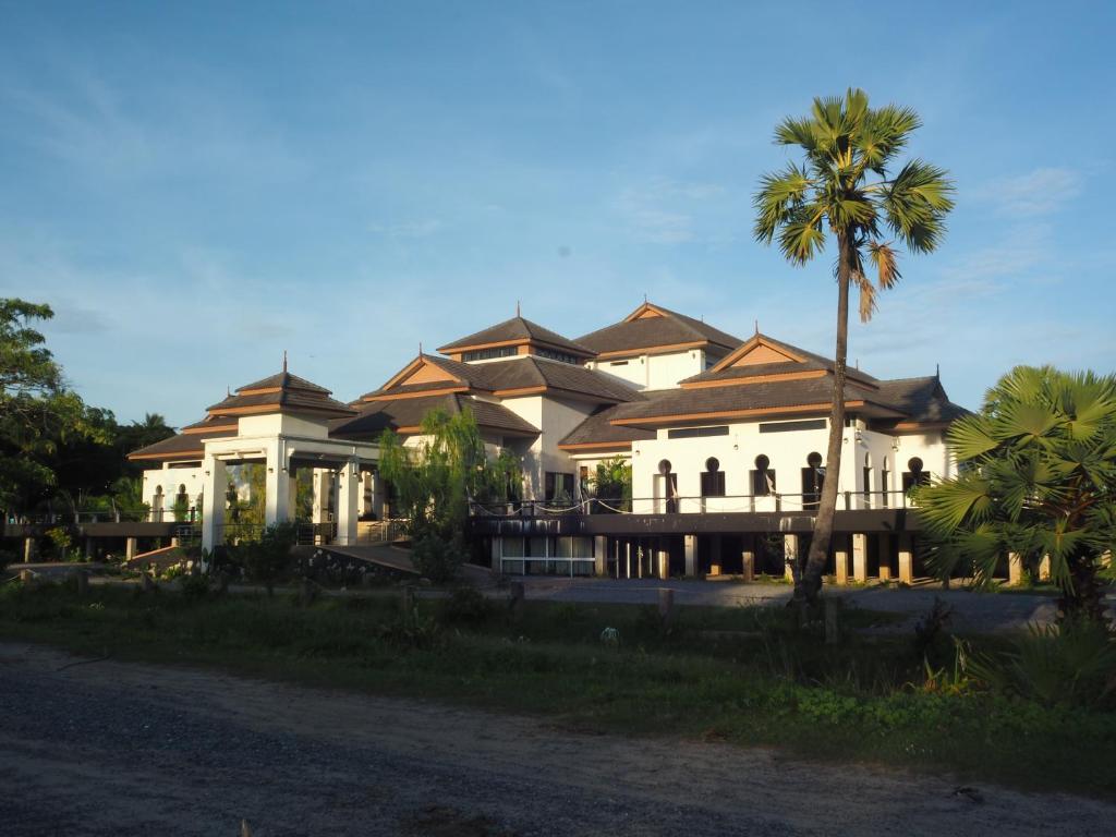 Pattani巴卡兰农场度假村的一座大建筑,前面有棕榈树