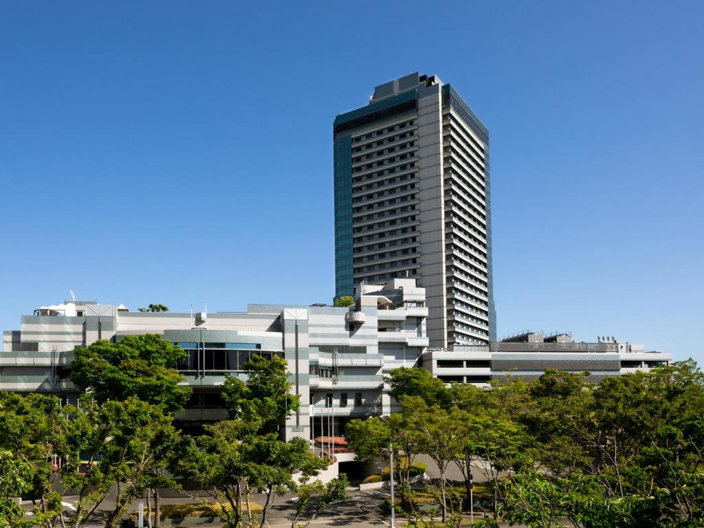 大阪Grand Prince Hotel Osaka Bay的前面有树木的高楼