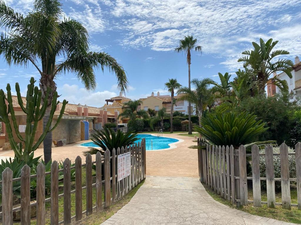 萨阿拉德洛斯阿图内斯BRISA DE ZAHARA - Casa para familia con piscina y garaje en Urb. privada的通往棕榈树游泳池的围栏