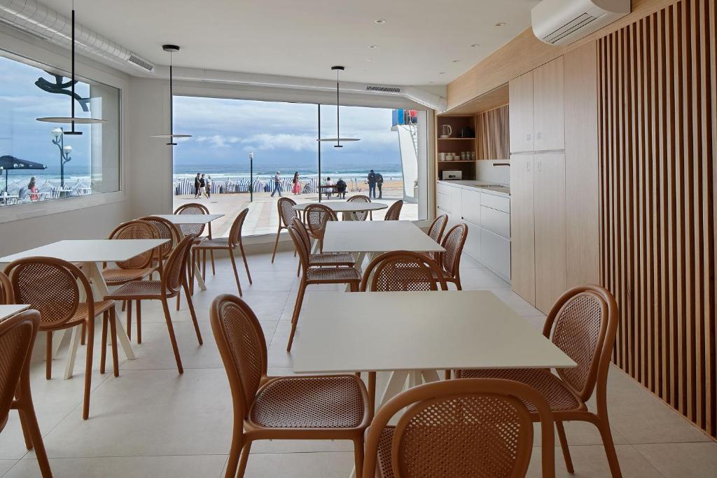 扎鲁亚斯Kein Hostel的一间带桌椅的餐厅,享有海滩美景