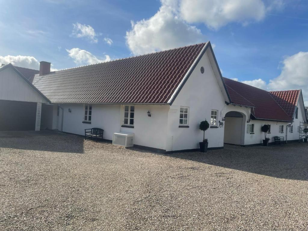 SvinningeDejlig lejlighed的白色的房子,有棕色的屋顶和车道