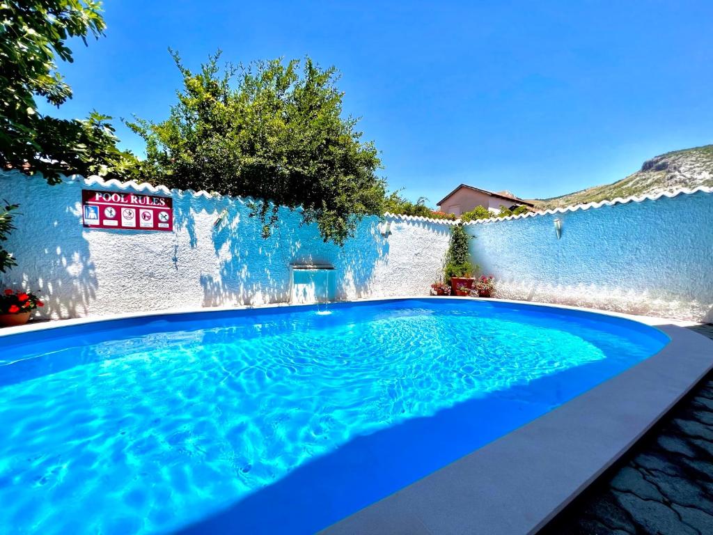 莫斯塔尔Hotel & Spa Villa Luxe的白色墙壁前的蓝色游泳池