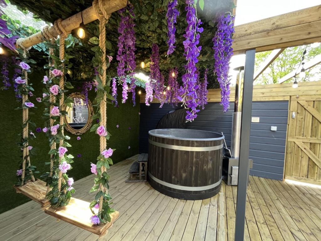 康福斯Wonderland Retreats的一个带顶棚的甲板,上面有桶和紫色的鲜花