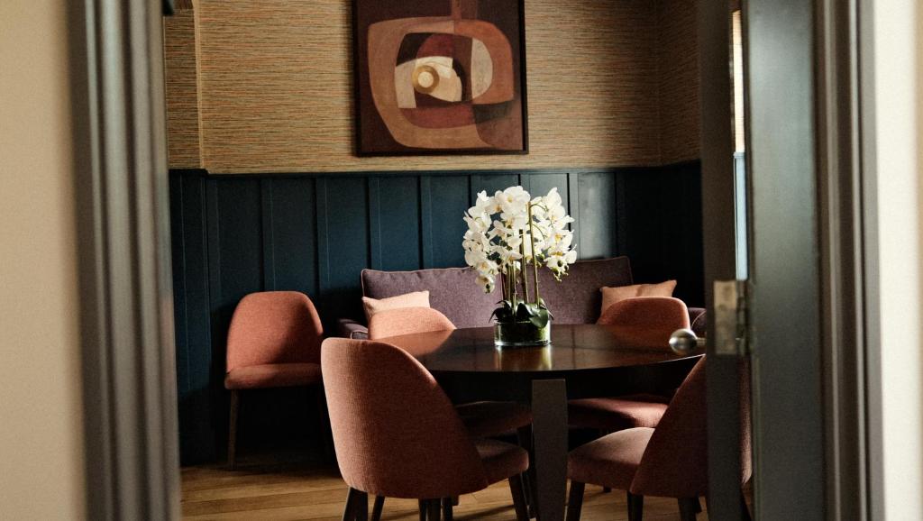 哈罗盖特劳伦斯奢华公寓式酒店 - 哈罗盖特的一间带桌椅和花瓶的用餐室